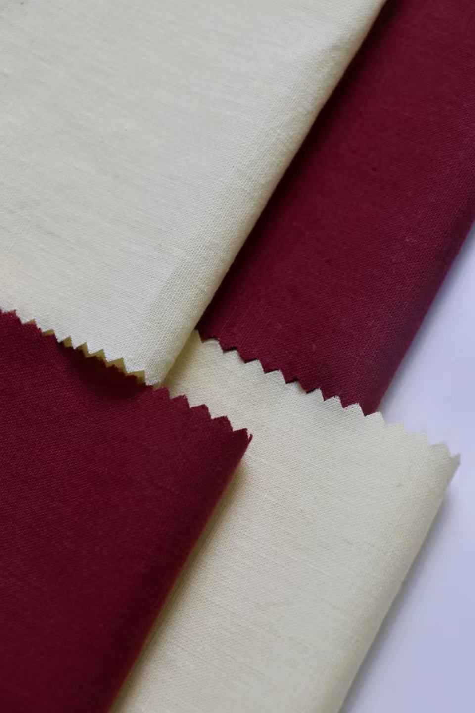 Overlapping deep red and pale cream fabric samples with zigzag edges