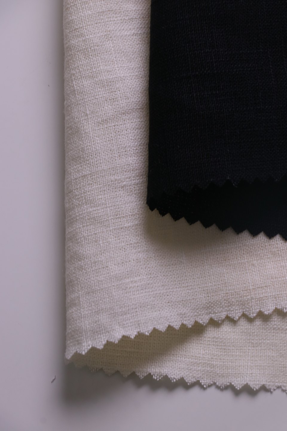 Black fabric layered over folded light-coloured fabric samples